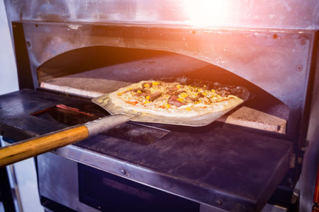The process of making pizza. Chef baker puts raw pizza in the oven. Kitchen.
