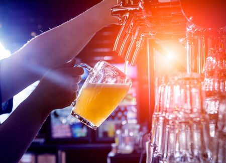 Bartender pouring draft beer at glasses in the bar. Restaurant.の写真素材