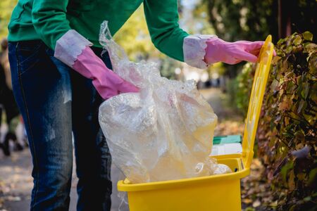 Volunteer girl sorts garbage in the street of the park. Concept of recycling.の写真素材