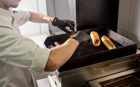 The chef cooking two hot dogs on a grill. Restaurant. Backgroundの写真素材