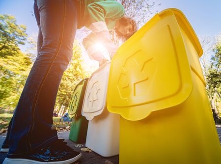 Volunteer girl sorts garbage in the street of the park. Concept of recycling. Zero waste concept. Nature backgroundの写真素材