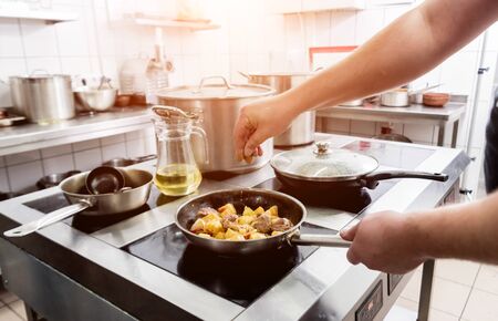 Chef cooks fried potatoes with pieces of meat in a restaurant kitchen. European cuisine. Backgroundの写真素材
