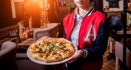 Waiter, carrying dish with tasty pizza with chicken and vegetables. Restaurant.の写真素材