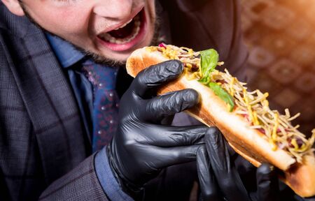 Hungry young man eating a hot dogs in cafe. Background. Restaurantの写真素材
