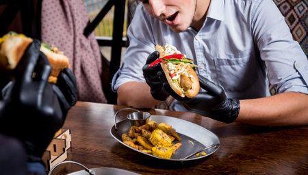 Two hungry young men eating a hot dogs in cafe. Background. Restaurant