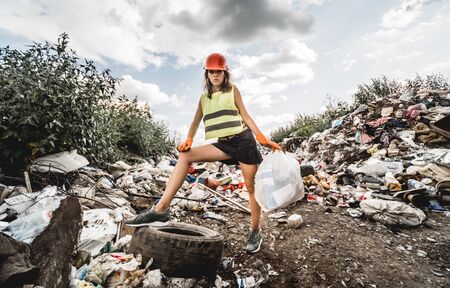 Woman volunteer helps clean the field of plastic garbage and old tires.の写真素材
