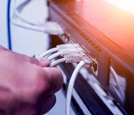 Technician connecting network cables to switches. Connecting cables