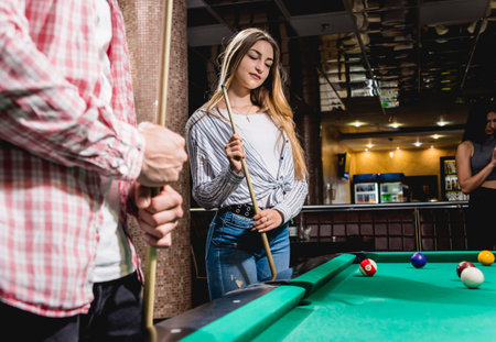 Young woman playing in billiard. Posing near the table with a cue in her hands