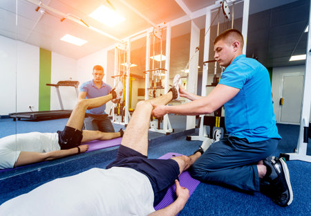 Rehabilitation therapy. Young man doing exercises on matの写真素材