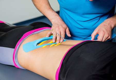 Kinesiotaping. Physical therapist applying tape to young beautiful womans spine. Physiotherapy.