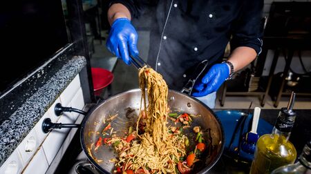 Chef cooking pasta with vegetables in pan. Italian style cuisine. Restaurant. Backgroundの写真素材