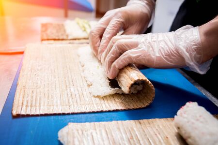 Process of making sushi and rolls at restaurant kitchen. Chefs hands with knife.の写真素材