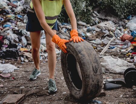 Woman volunteer helps clean the field of plastic garbage and old tires.の写真素材