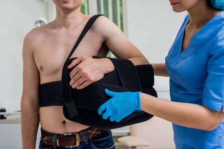 Nurse putting a sling on patients arm that is broken. Injury. Broken arm, shoulder. Arm fix braceの写真素材