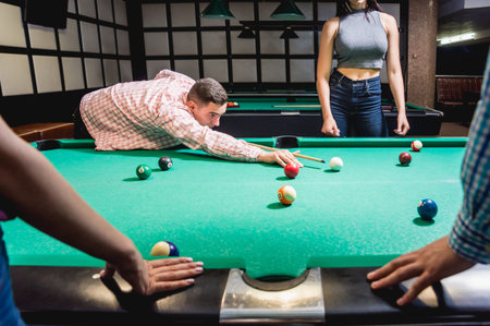 Young man trying to hit the ball in billiard.
