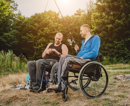 Handicapped men fishing at a lake. Wheelchair. Camping.の写真素材