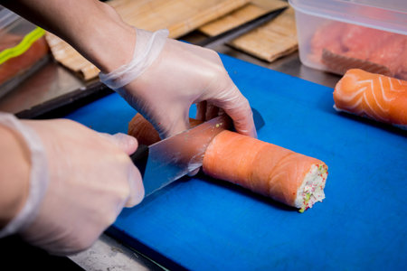 Process of making sushi and rolls at restaurant kitchen. Chefs hands with knife.の写真素材