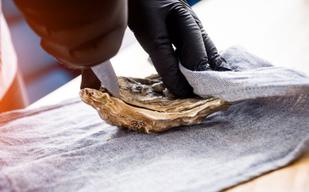 Chef opens a fresh oyster. Dish with open oysters. Restaurant. Background