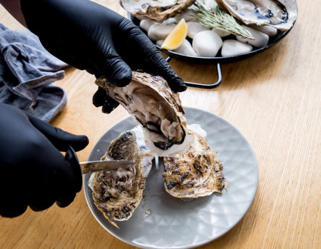 Chef opens a fresh oyster. Dish with open oysters. Restaurant.