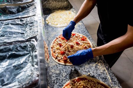 The process of making pizza. Hands of chef baker making pizza at cafe kitchenの写真素材
