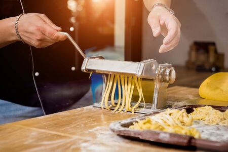 Chef rolling dough with a pasta machine. Pasta maker machine. Homemade italian style cuisine. Restaurant. Backgroundの写真素材