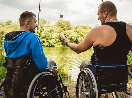 Handicapped men fishing at a lake. Wheelchair. Camping.の写真素材
