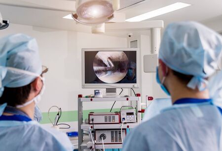 Arthroscope surgery. Orthopedic surgeons in teamwork in the operating room with modern arthroscopic tools. Knee surgery. Hospital backgroundの写真素材