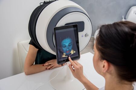 Face skin analyze system. Cosmetologist analyzing woman face.の写真素材