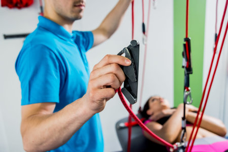 Physiotherapy. Suspension training therapy. Young woman doing fitness traction therapy with...