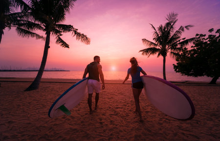 Two young surfers going into the sea with surf boards