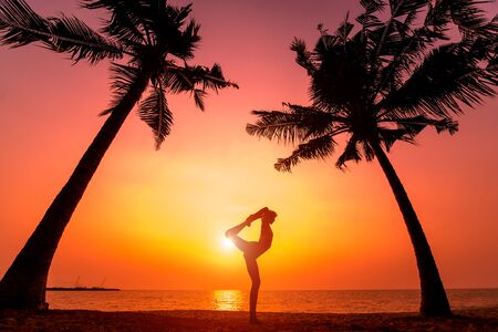 Beautiful young woman practic yoga at the beach. Early morning exercise. Sunriseの写真素材