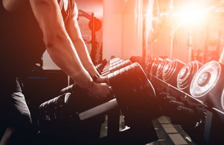 Handsome muscular man working out with dumbbells.の写真素材