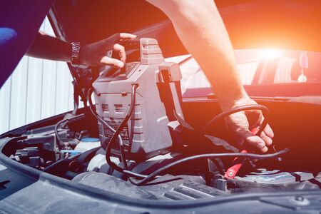 Accumulator charging. Hands and terminal. Car and repair. Service station.の写真素材