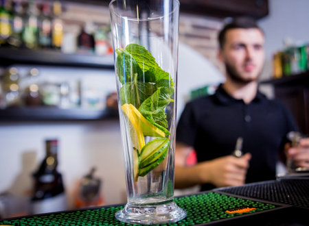 Bartender is making non alcoholic cocktail at bar counter.
