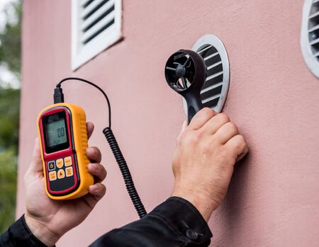 Technician use hand-held anemometer measuring air flowing measurementの写真素材