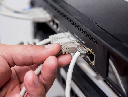Technician connecting network cables to switches. Connecting cablesの写真素材