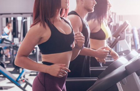 Young peoples training on treadmill at the gym. In fitness center. Health concept