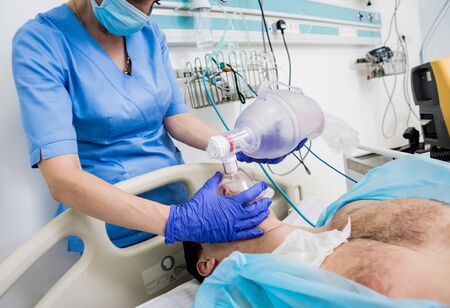 Doctors give resuscitation to a male patient in the emergency room. Cardiac massage. Defibrillationの写真素材