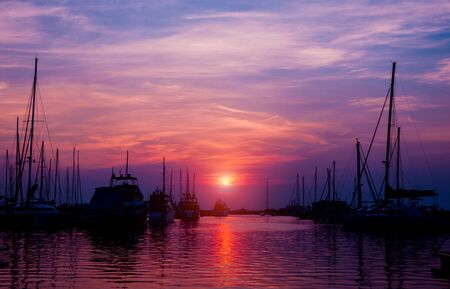 Beautiful view of marina and harbor with yachts and motorboats. Sunset at the ocean. Backgroundの写真素材
