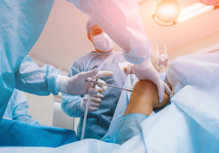 Arthroscope surgery. Orthopedic surgeons in teamwork in the operating room with modern arthroscopic...