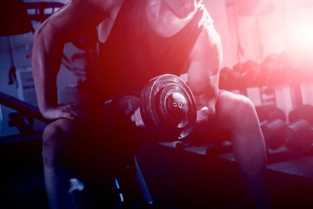 Handsome muscular man working out with dumbbells.の写真素材