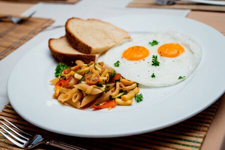 Fried eggs with pasta on the white plateの写真素材