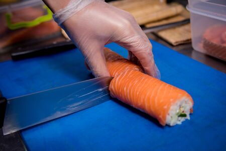 Process of making sushi and rolls at restaurant kitchen. Chefs hands with knife. Backgroundの写真素材