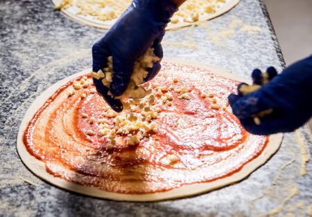 The process of making pizza. Hands of chef baker making pizza at cafe kitchenの写真素材