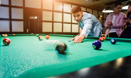 Young man trying to hit the ball in billiard.の写真素材