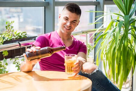 Young man in the pub. Drinking beer, eating pizza.の写真素材