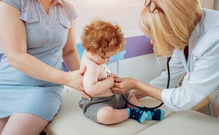 Friendly doctor pediatrician with patient child at clinicの写真素材