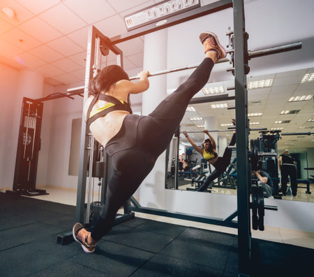 Beautiful athletic young woman making exercise at the gym.