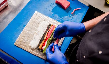 Process of making sushi and rolls at restaurant kitchen. Chefs hands with knife.の写真素材