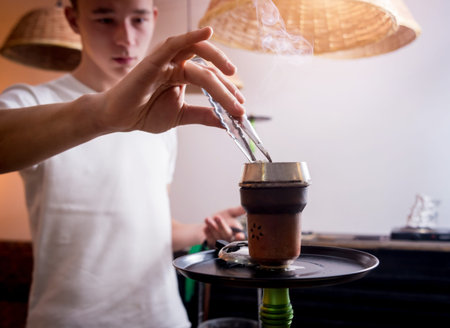 Cooking hookah in the bar. Young man with hookah in restaurant